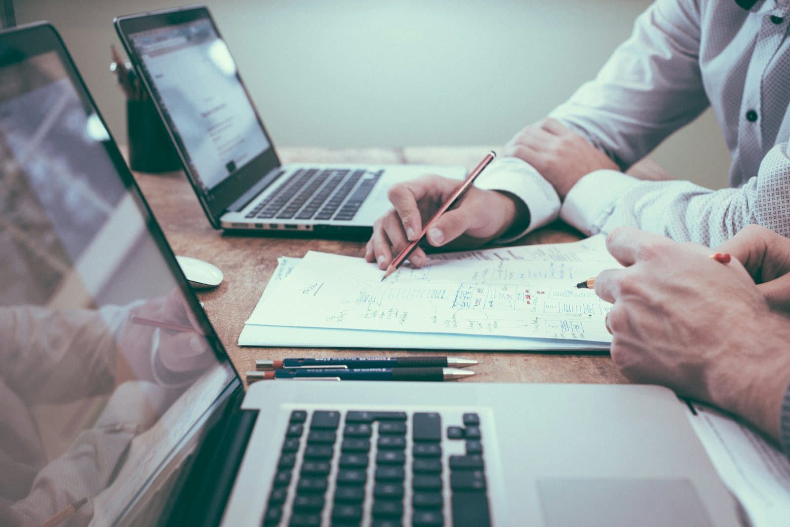 Hands working through printed financial statements beside a laptop