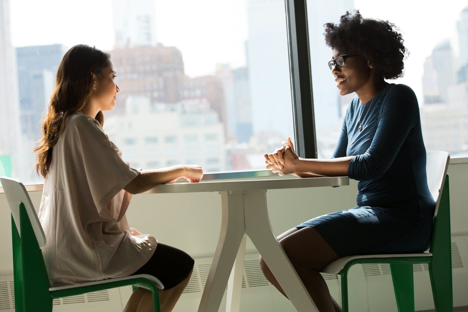 Two colleagues read through a draft together at a table by a window